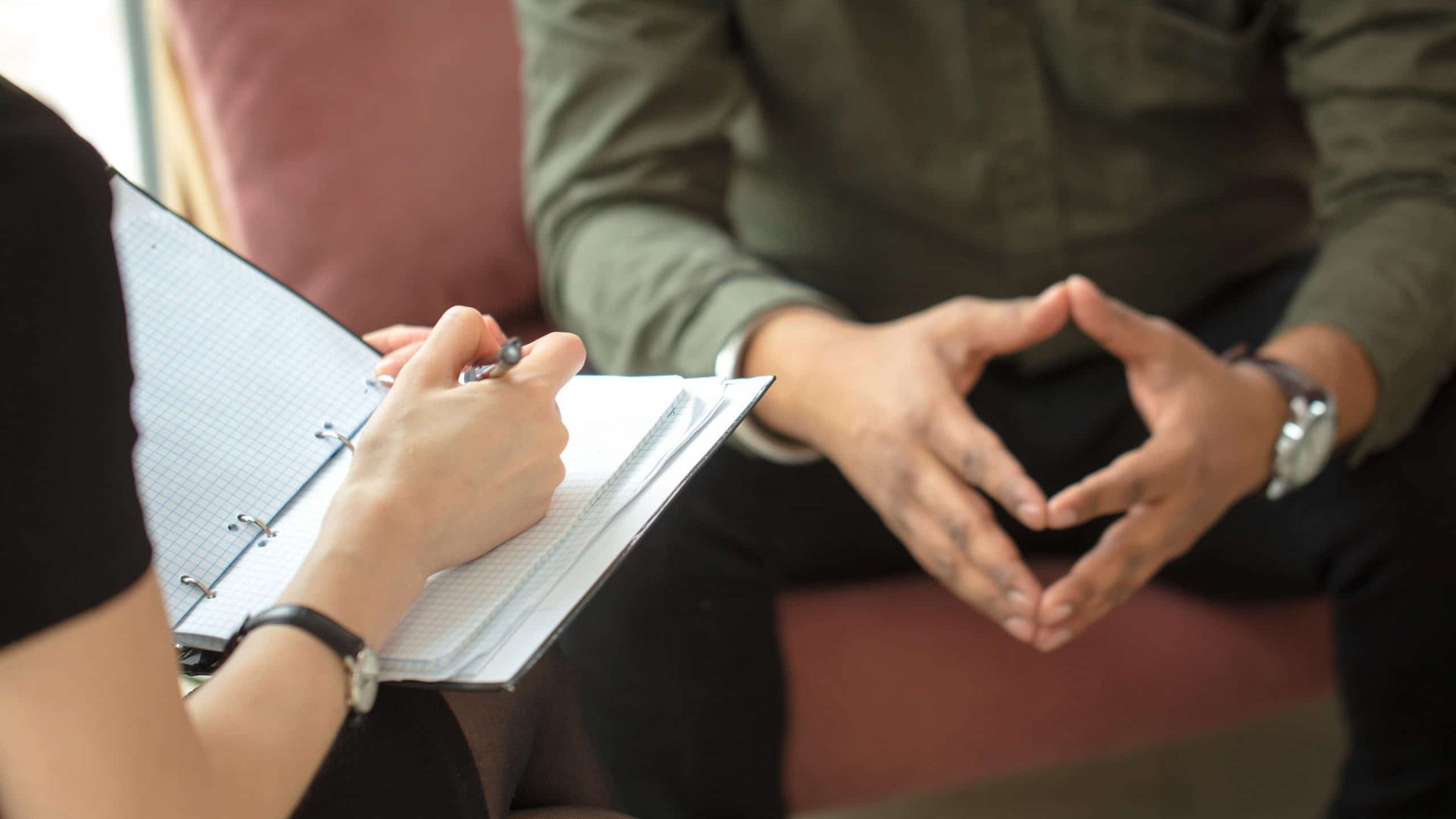 therapist writing down notes during therapy with her male patient